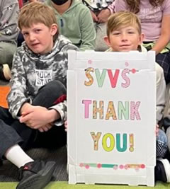 Children display a large "Thank You" sign for the storytellers.