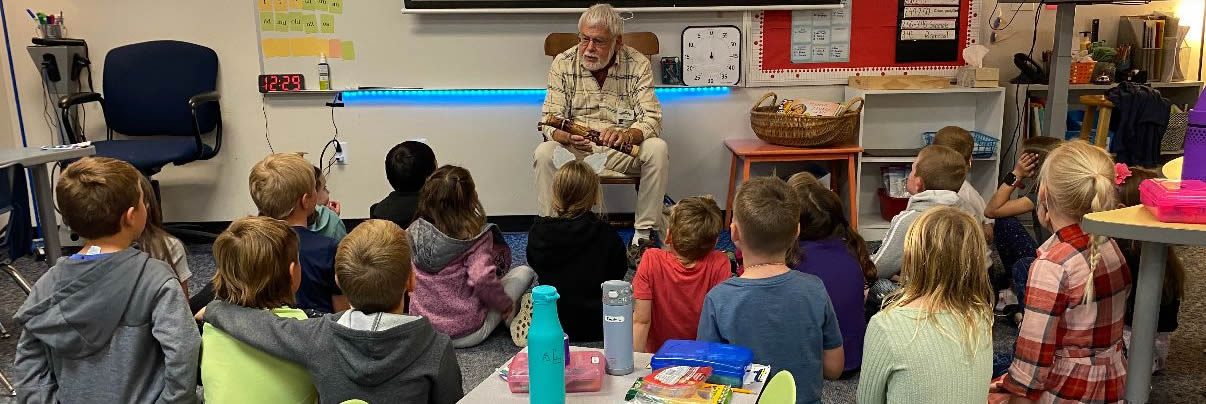 Storyteller quiets the children listeners with an shaker stick. Other storytellers use different ways to grab the kids attention and get them ready to listen.